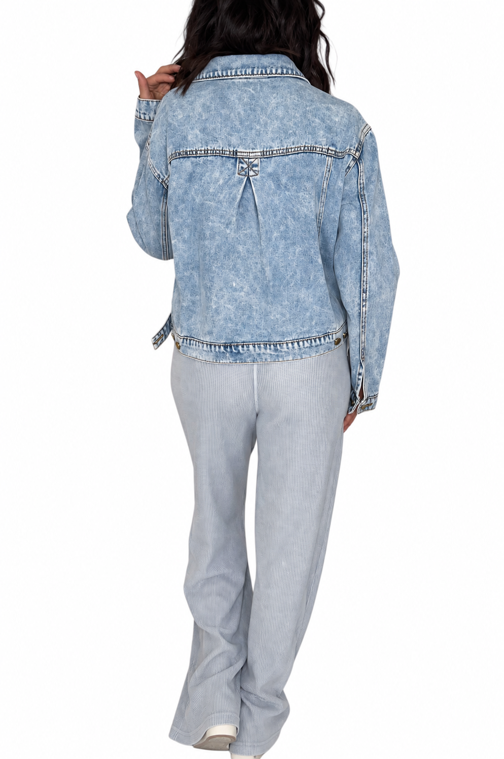 Back profile of a woman wearing waffle light blue casual pants with a drawl string and front pockets with a brown tank and jean jacket on a white background