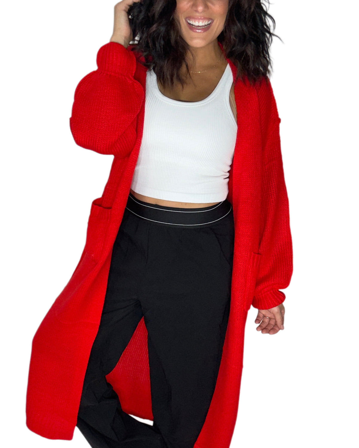A woman wearing a bright red open-front knit cardigan over a white crop top and black pants, shown against a plain white background.
