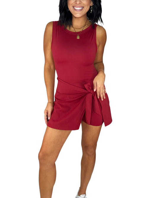 Woman wearing a red dress active romper with a tie waist on a white background