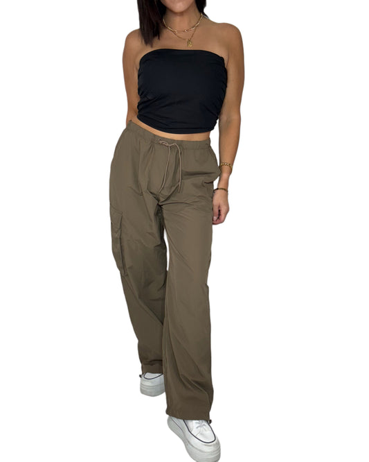Woman wearing a black strapless top and brown high-waisted cargo pants on a white background