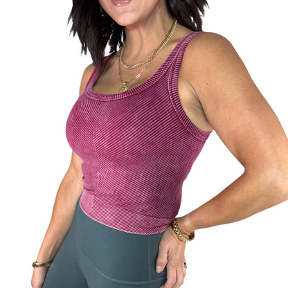 Woman wearing a maroon ribbed tank top and green leggings on a white background