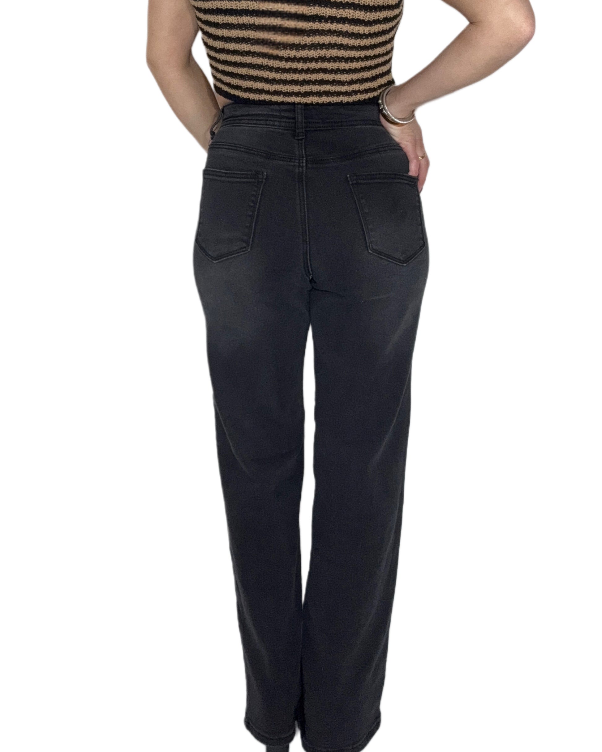 Back profile of a woman wearing black high-waisted jeans on a white background