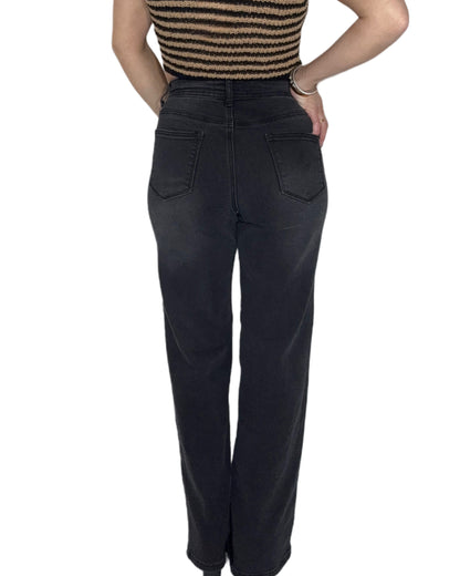 Back profile of a woman wearing black high-waisted jeans on a white background