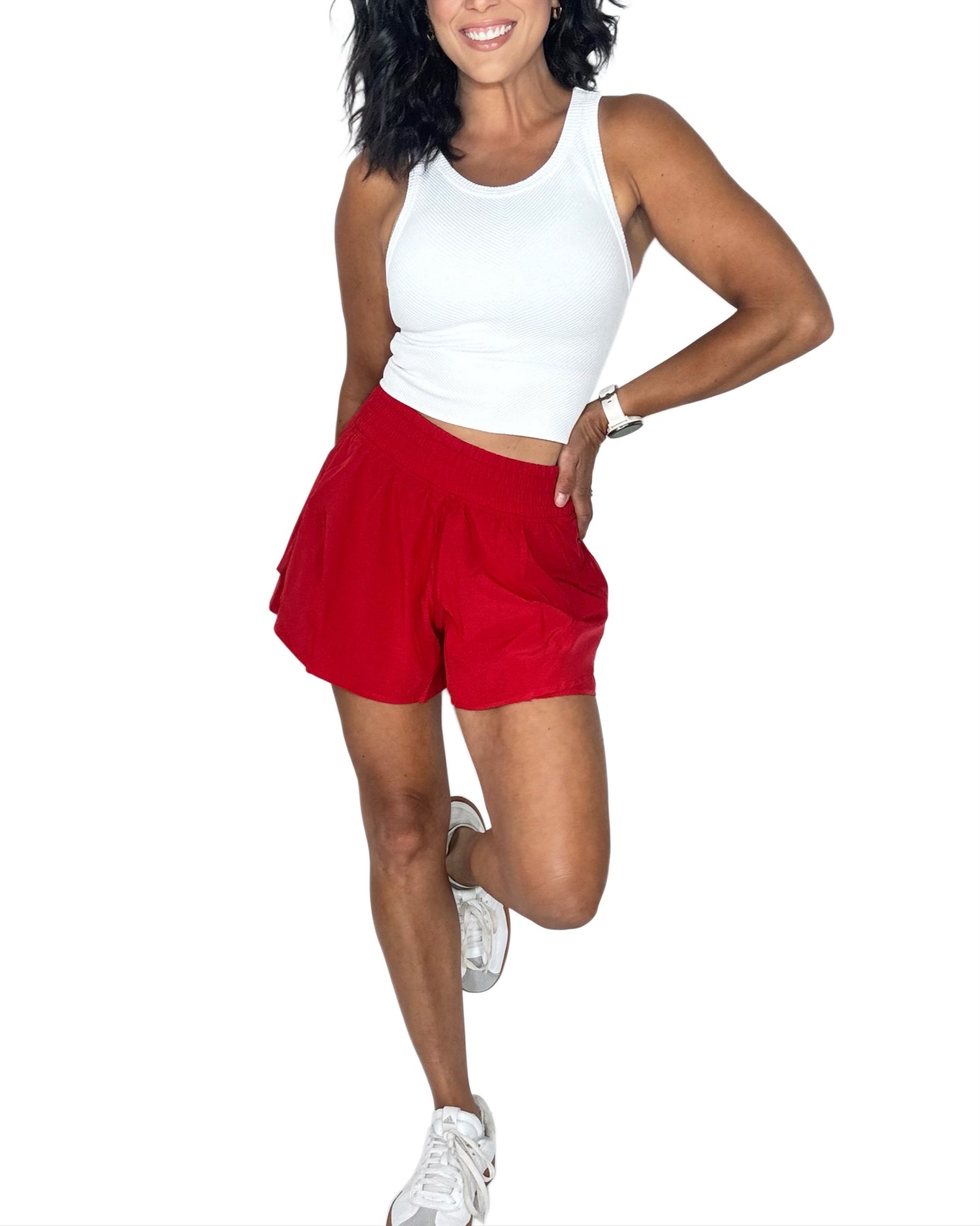 Woman wearing a white tank top and red shorts on a white background