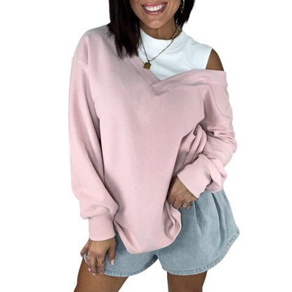 Woman wearing a pink oversized top with a white drop shoulder on a white background