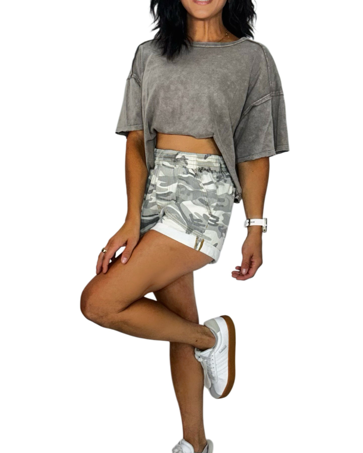 Woman wearing a gray oversized t-shirt and camouflage shorts on a white background