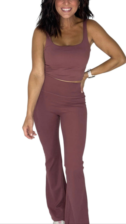 Woman wearing a rosewood active pant set with matching tank and flared bottoms on a white background 