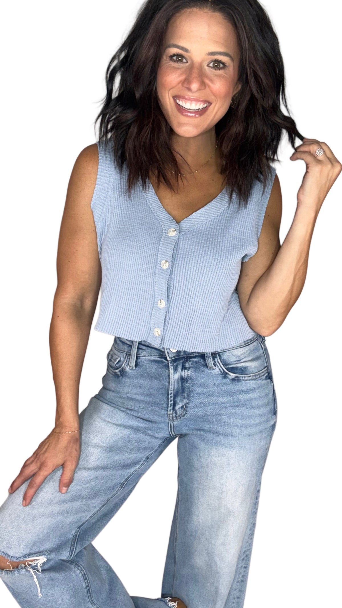 Woman wearing a light blue waffle sleeveless top with medium wash jeans, on a white background