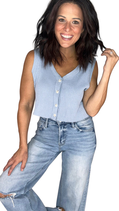 Woman wearing a light blue waffle sleeveless top with medium wash jeans, on a white background