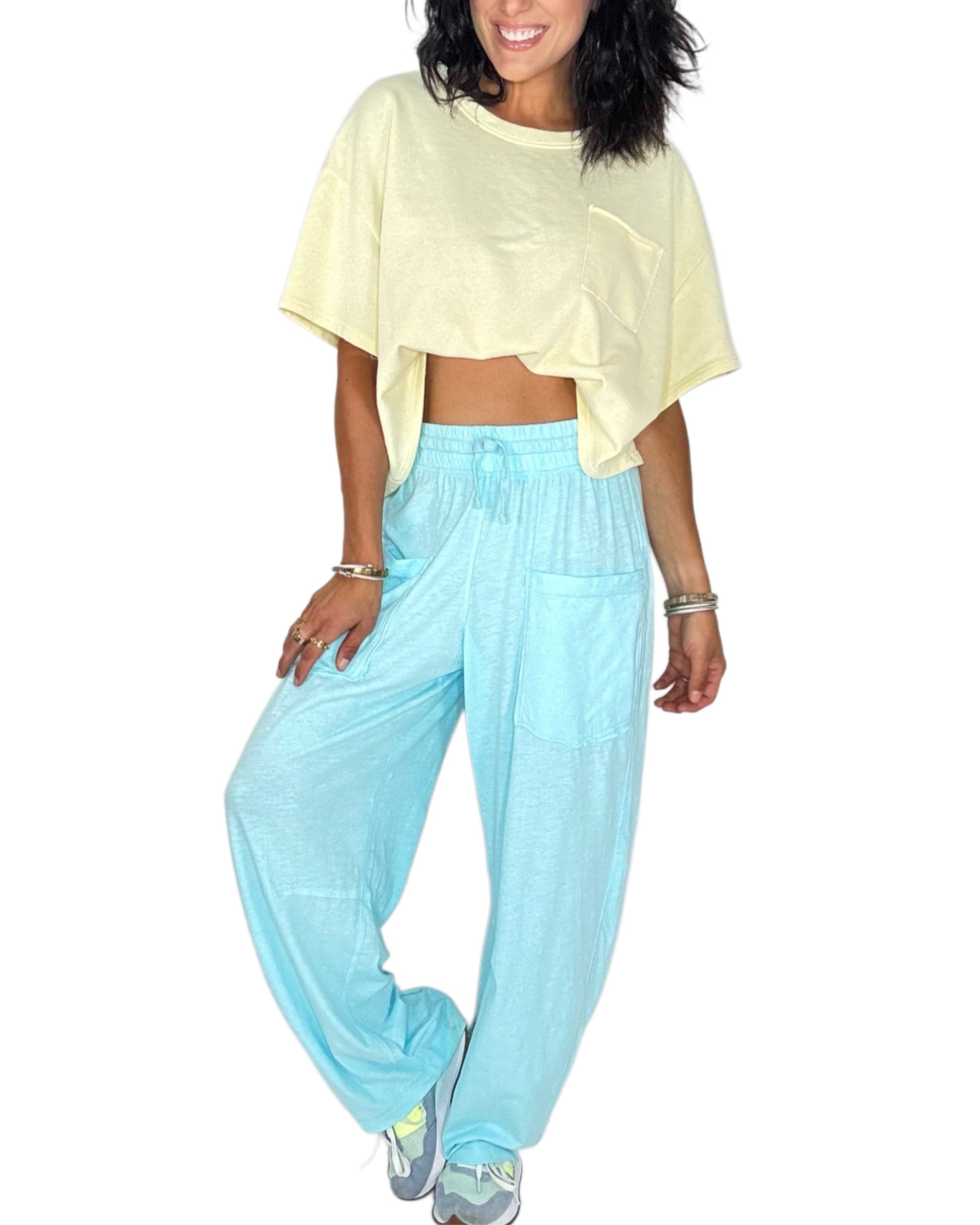 Woman wearing bright blue sweat pants with a yellow tee on a white background