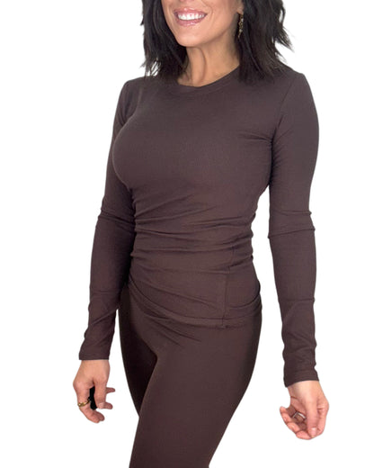 Woman wearing a brown long-sleeve top and leggings on a white background