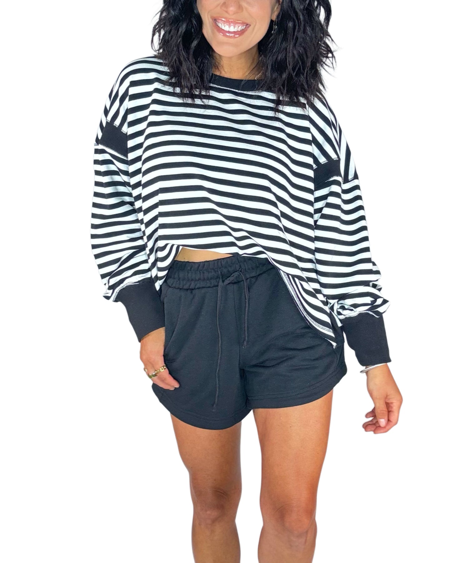 Woman wearing black terry shorts with a striped black and white sweatshirt on a white background