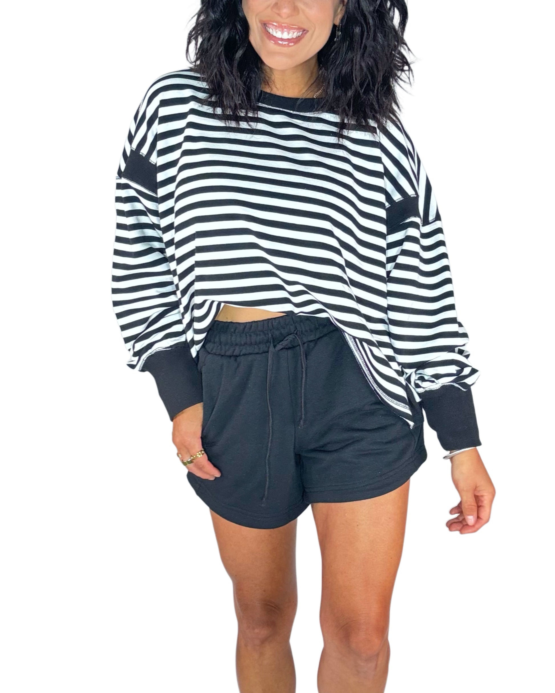 Woman wearing black terry shorts with a striped black and white sweatshirt on a white background