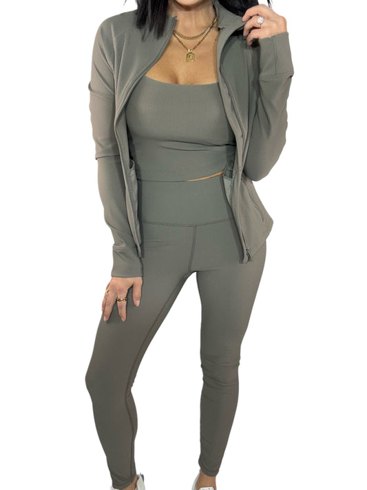 Close up of a woman wearing a 3 piece green ribbed athletic outfit on a white background