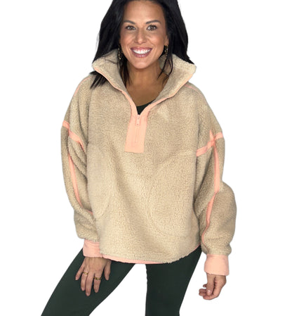 Woman wearing a taupe and peach fleece pullover on a white background