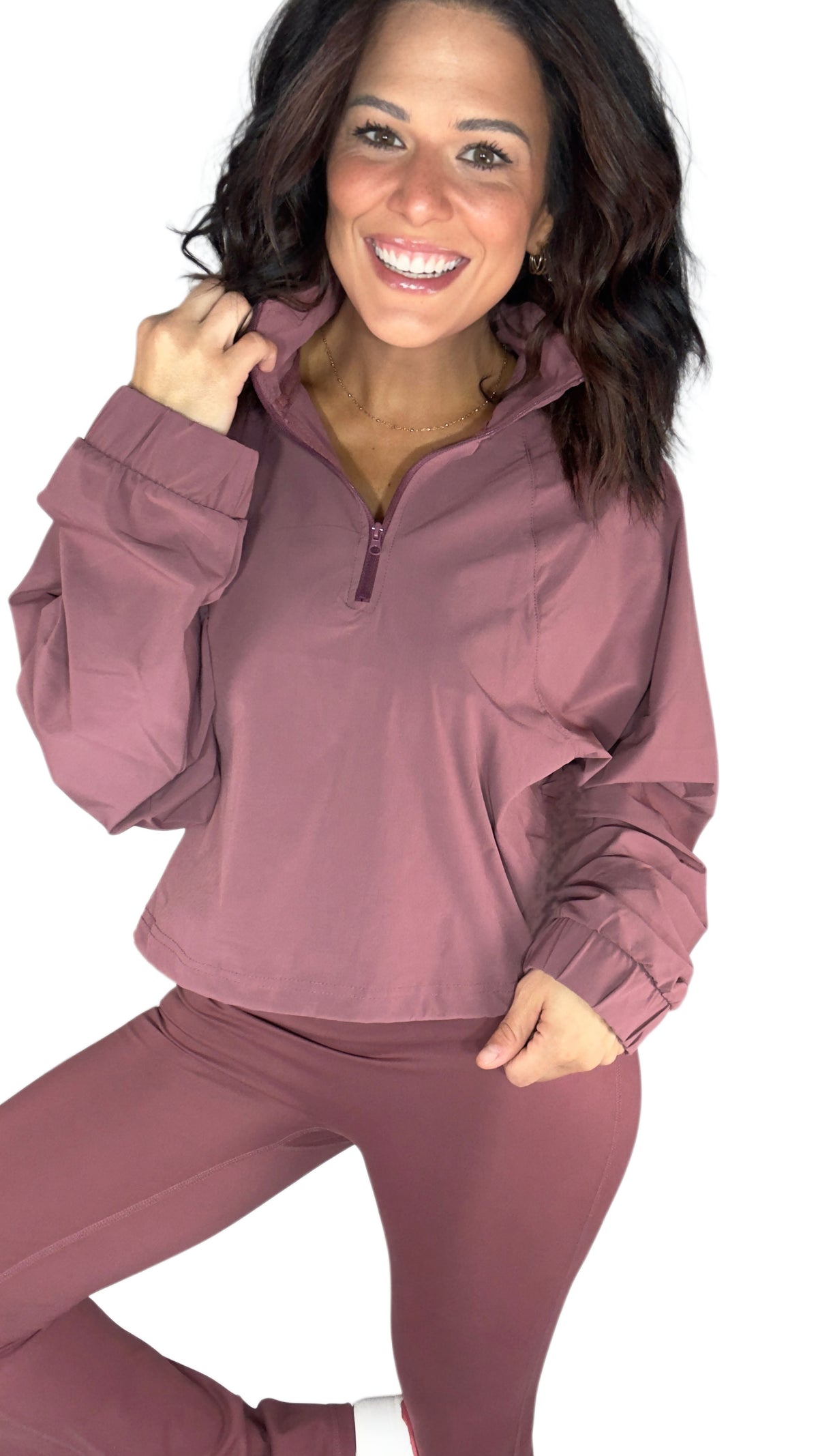A woman wearing an active half zip with matching leggings in rosewood mauve on a white background 