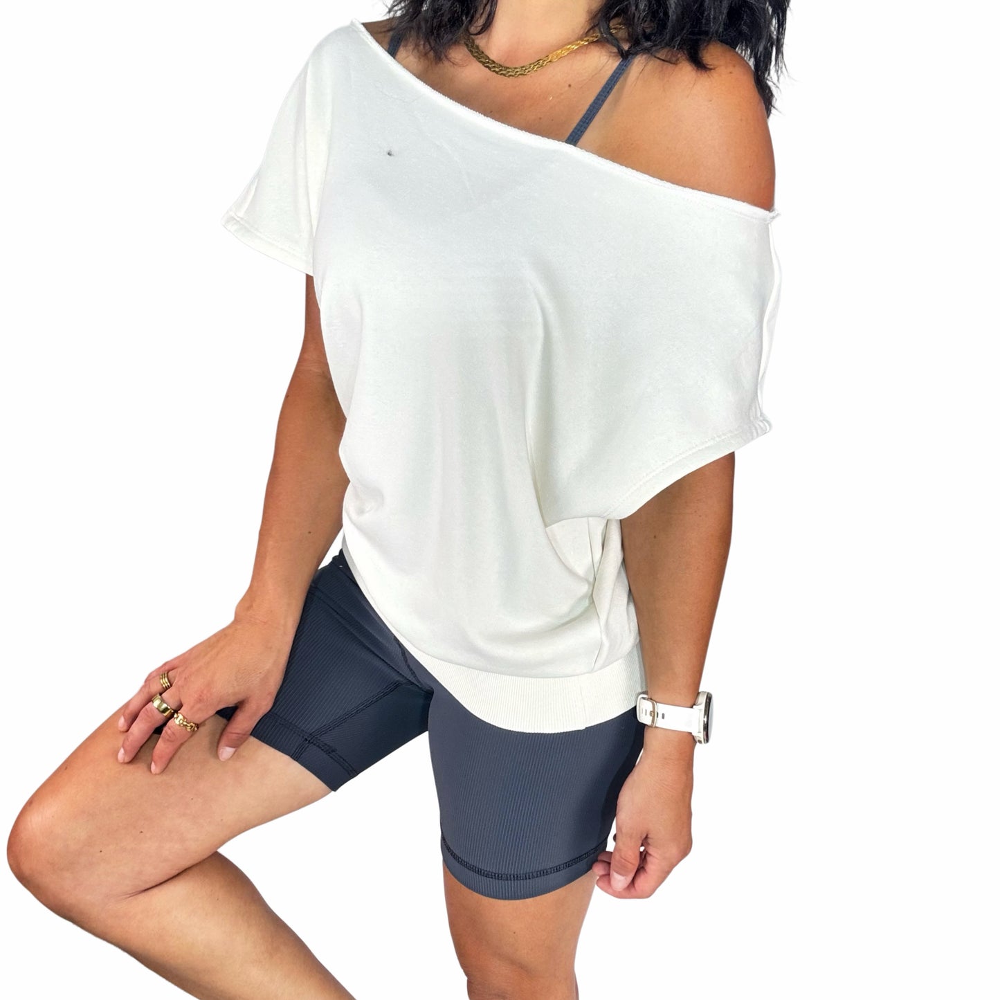 Person wearing a white off-shoulder top and dark gray bike shorts on a white background
