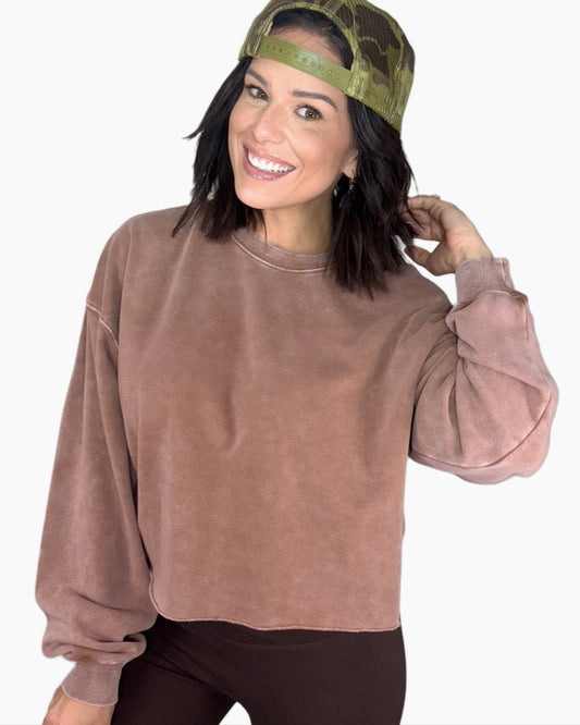 Woman wearing a mauve sweatshirt and green cap on a white background
