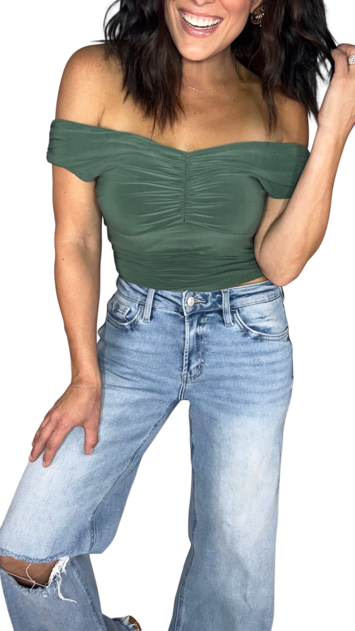 A woman wearing a olive green off the shoulder crop top with medium washed jeans, on a white background