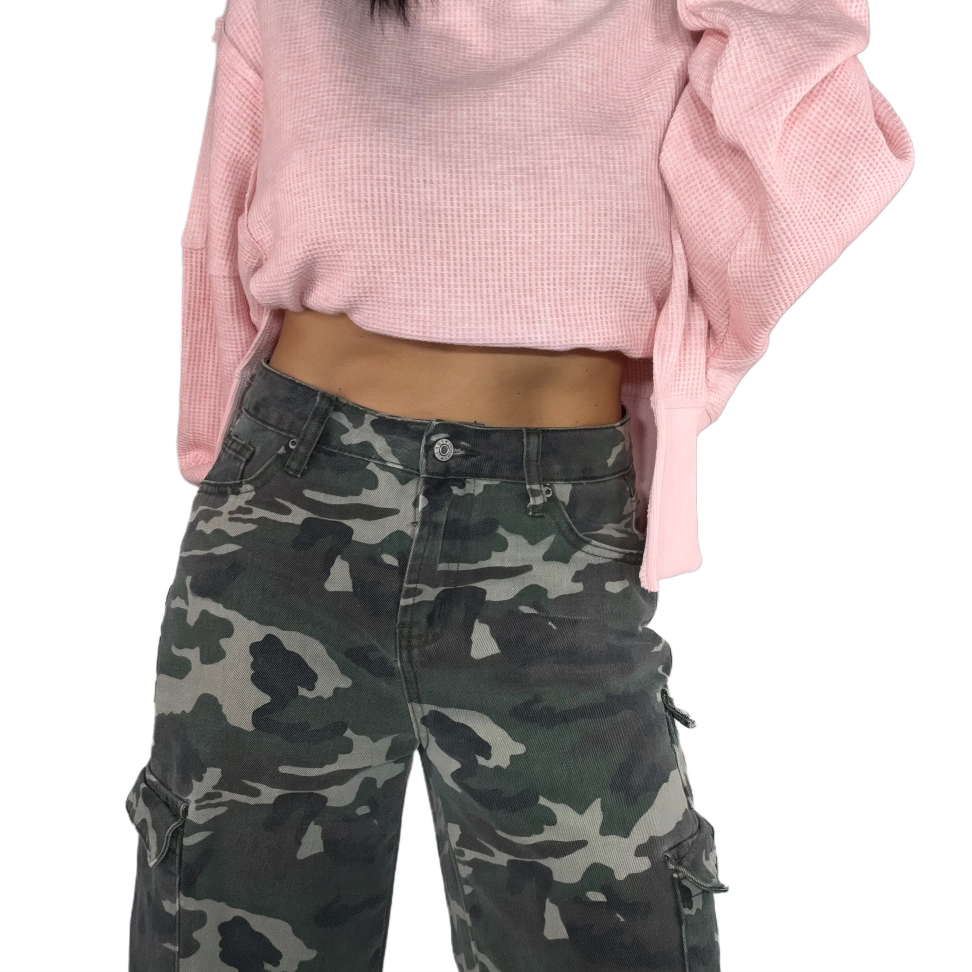 Close up of a woman wearing a pink cropped sweater and camouflage cargo pants on a white background