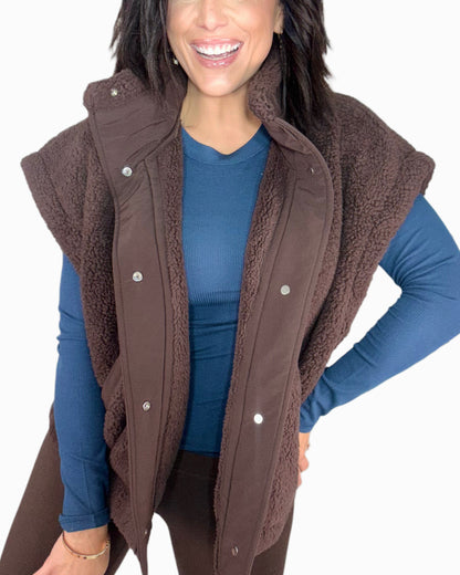 Woman wearing a brown vest over a blue shirt on a white background