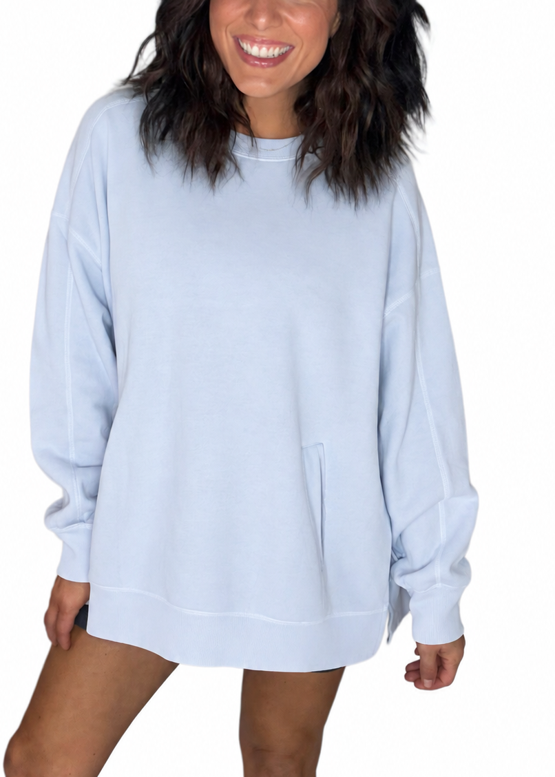 Woman wearing an oversized light blue sweatshirt on a white background 