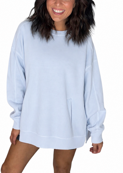 Woman wearing an oversized light blue sweatshirt on a white background 