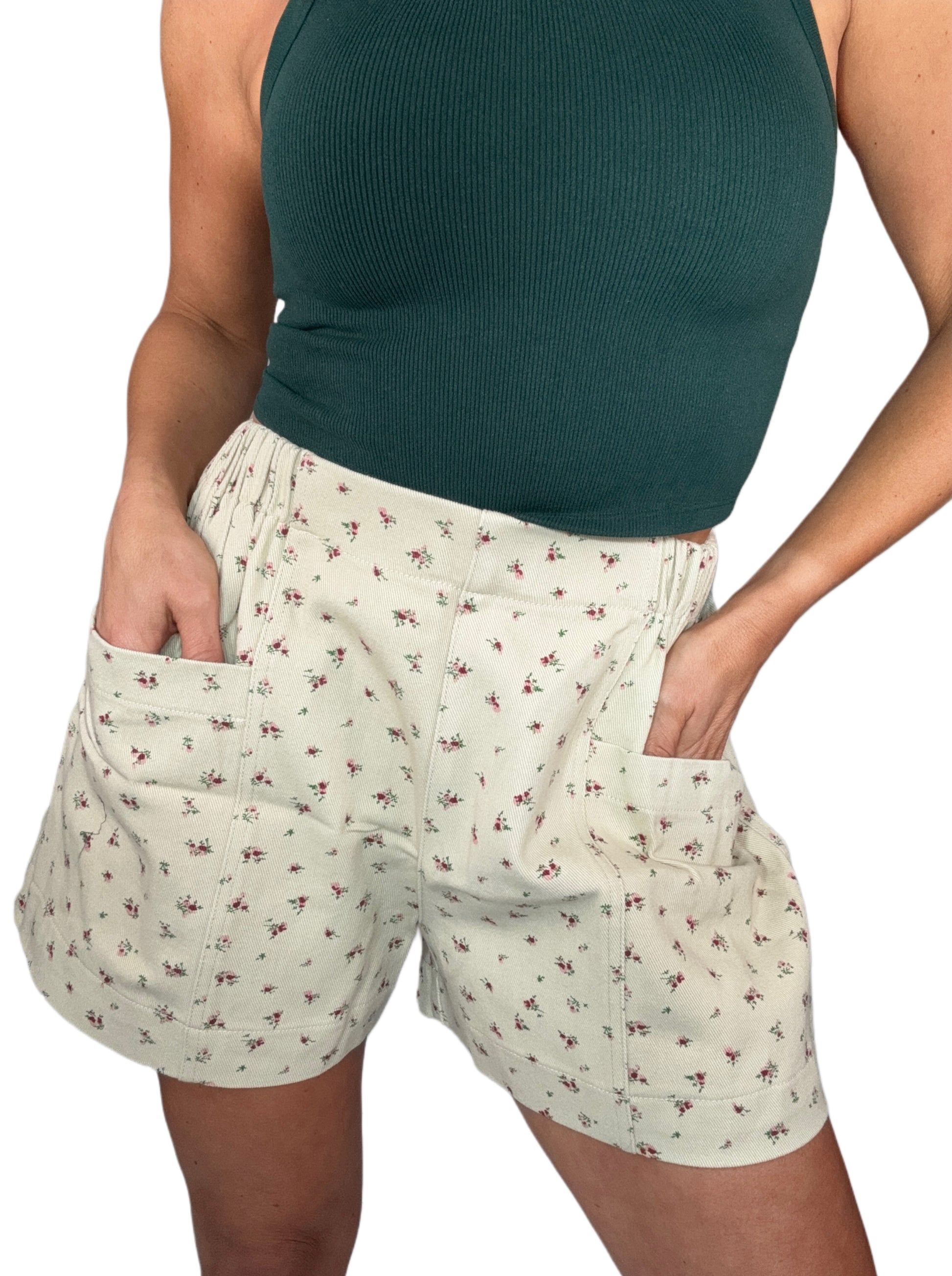 Woman wearing floral shorts and a green top on a white background