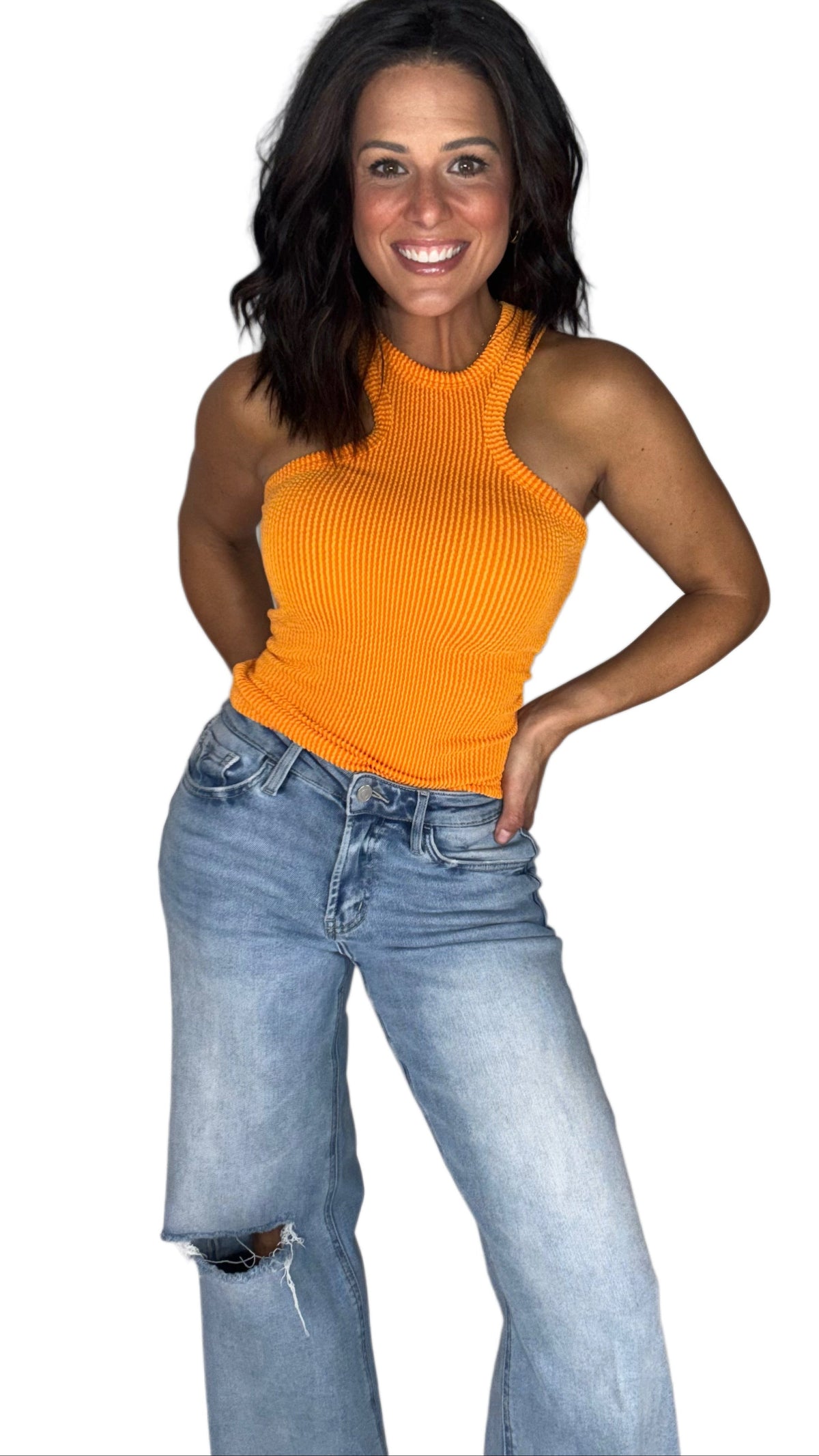 Woman wearing a ribbed Y cut  orange tank top with medium washed jeans on a white background