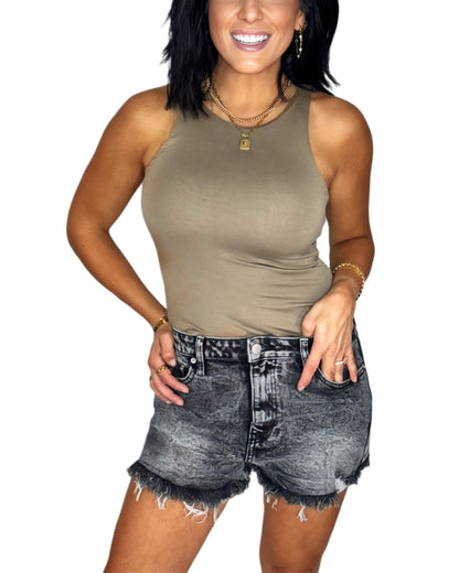 Woman wearing a mocha bodysuit with black denim jean short and a white background
