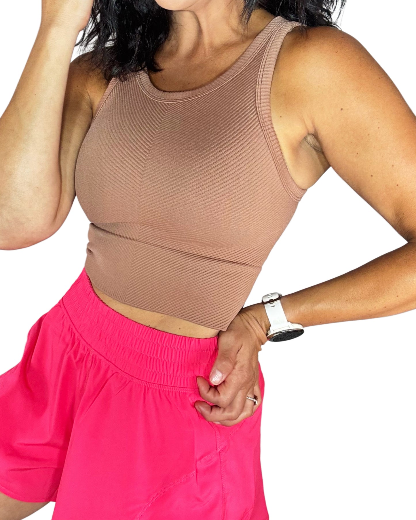 Woman wearing a beige top and pink shorts on a white background