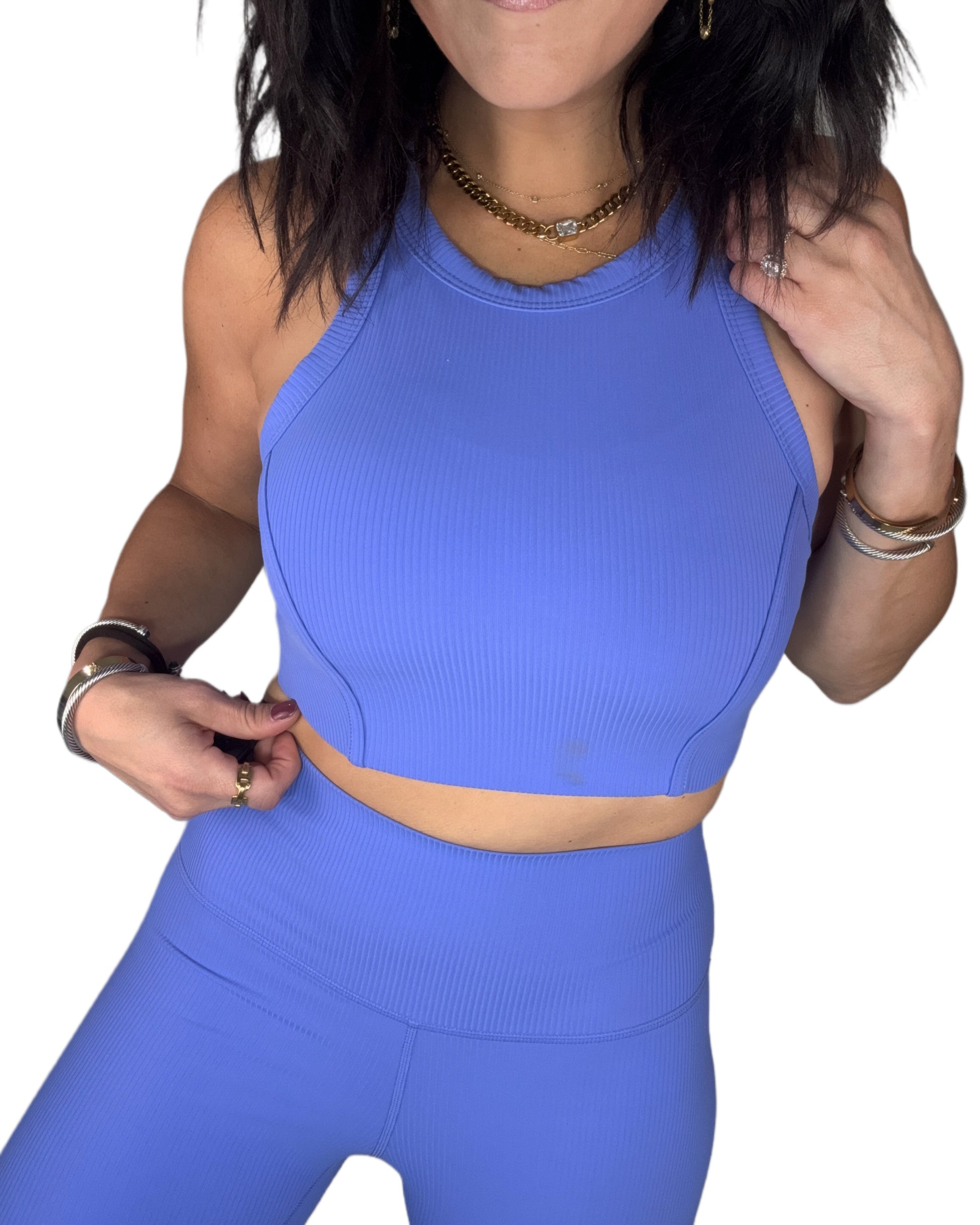 Close up of a woman wearing wearing a ribbed blue athletic outfit on a white background