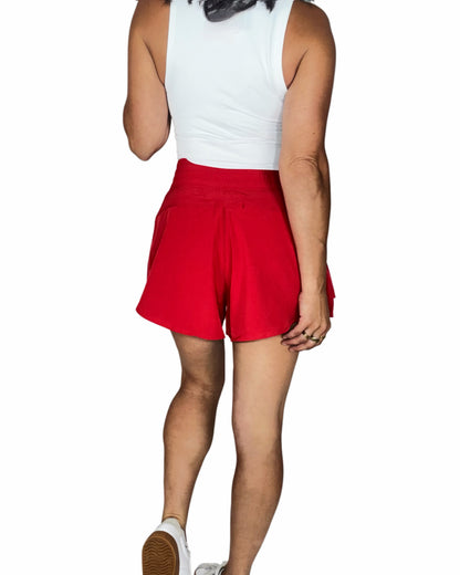 Person wearing red shorts and a white top on a white background