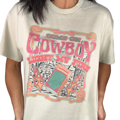 Close up of a woman wearing a sand t-shirt with colorful graphic design on a white background