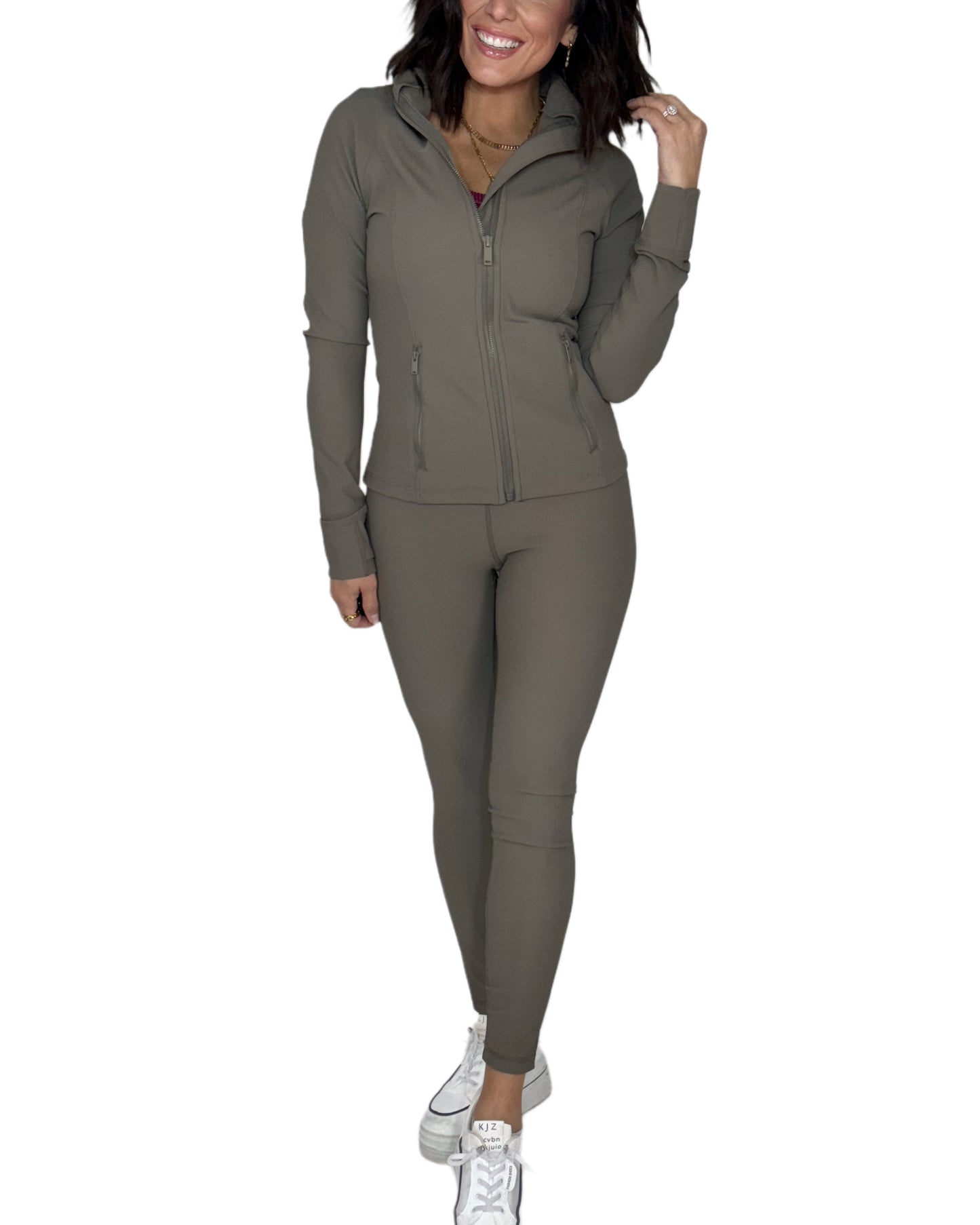 Zip-up look of a woman wearing a ribbed green athletic set on a white background