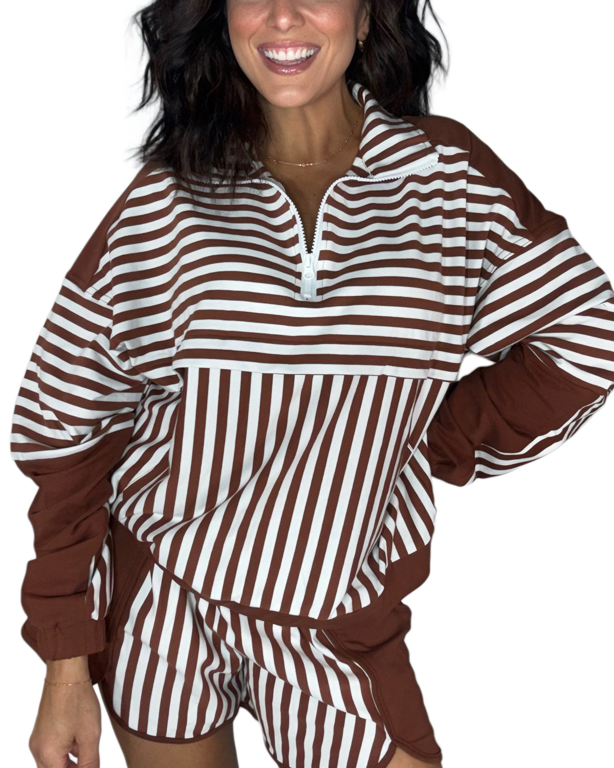 A woman wearing a brown and white striped long-sleeve top with a half-zip collar and matching striped shorts, shown against a plain white background.