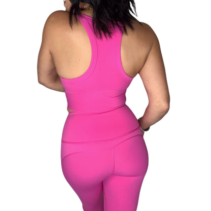 Back profile of a woman wearing a bright pink athletic outfit on a white background