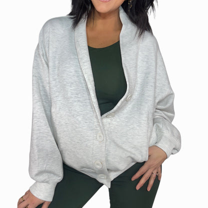 Woman wearing a gray cardigan over a green top and bottom set on a white background