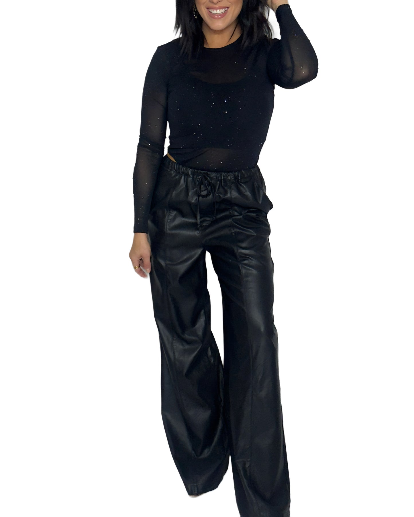 Woman wearing a black bodysuit with and black leather pants on a white background