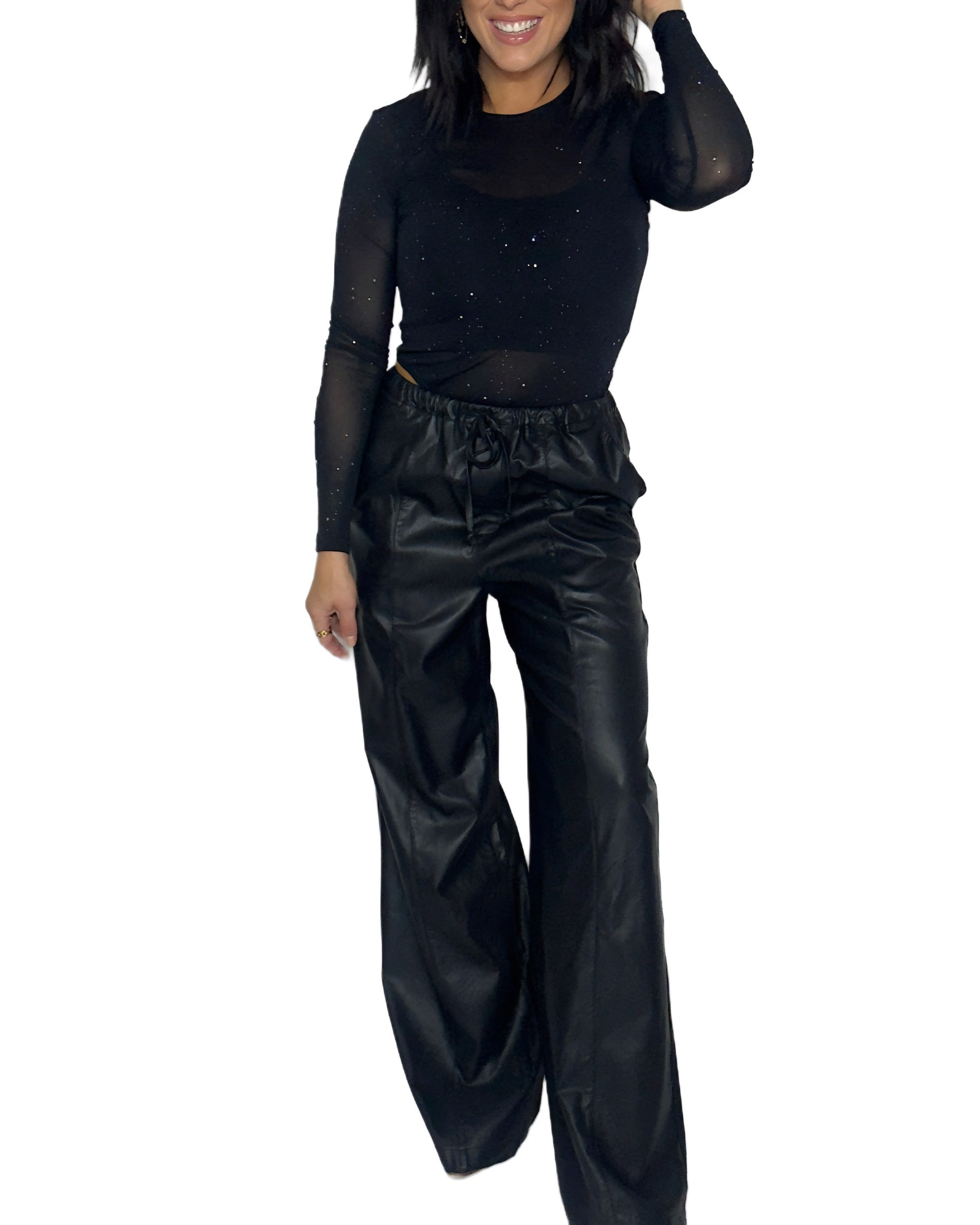 Woman wearing a black bodysuit with and black leather pants on a white background