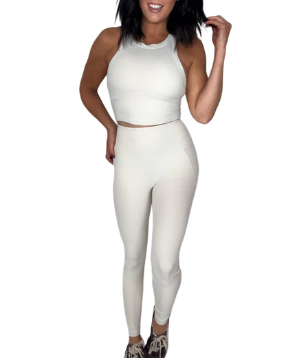 Woman wearing a off white athletic outfit on a white background