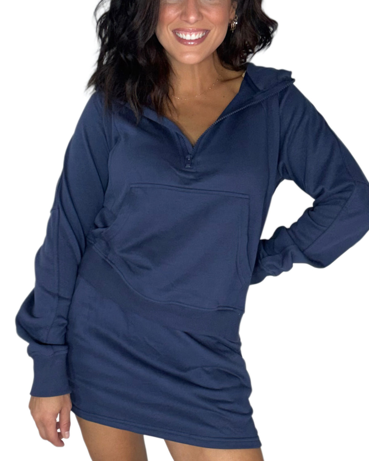 Woman wearing a navy half zip sweatshirt with kangaroo front pockets and a matching skort set, on a white background