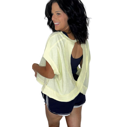 Woman wearing a pale yellow top with a key hole on the back, paired with navy shorts and navy tank on a white background