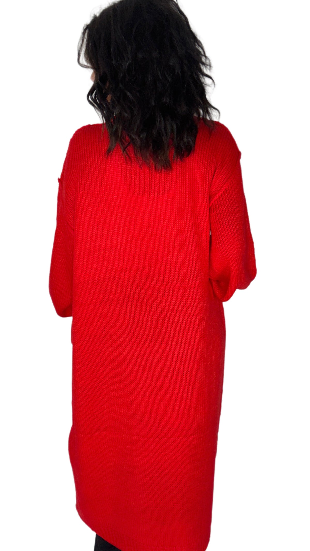 A person viewed from the back wearing a bright red ribbed knit sweater or long top against a plain white background.