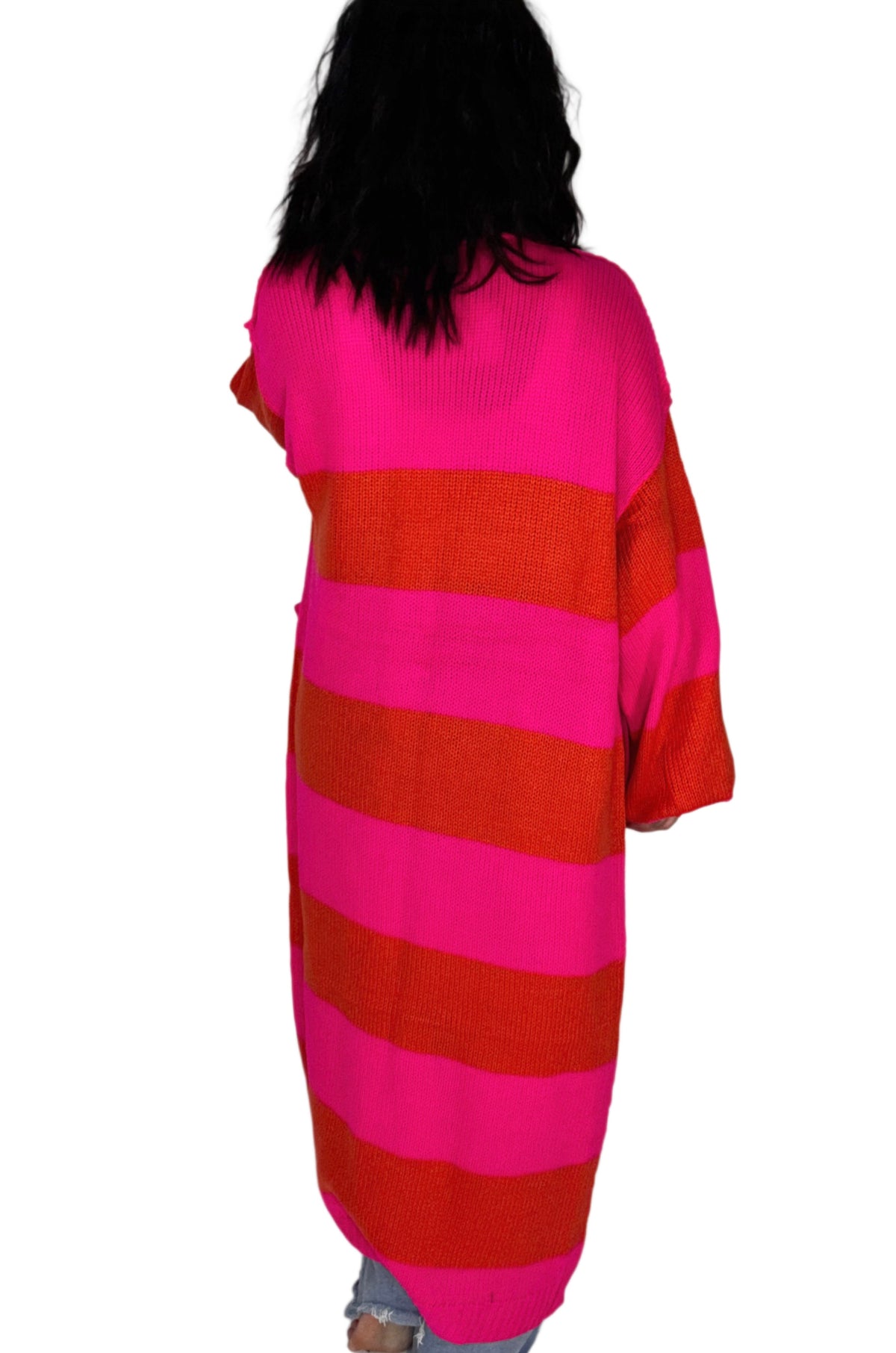Back profile of a woman wearing a pink and red cardigan on a white background 