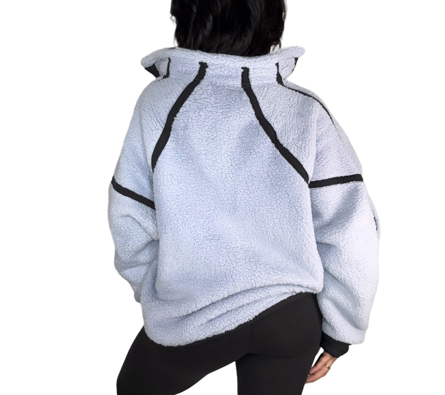 The back of a light blue fleece jacket with black accents on a white background