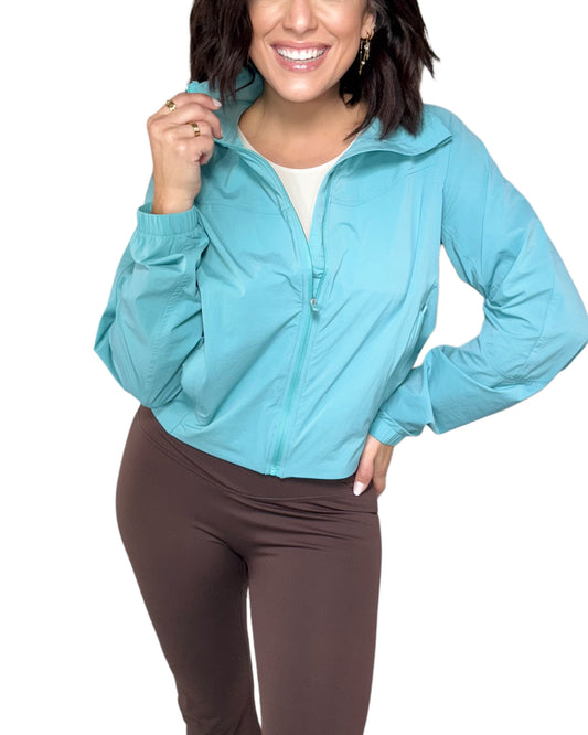 Woman wearing a aqua jacket on a white background