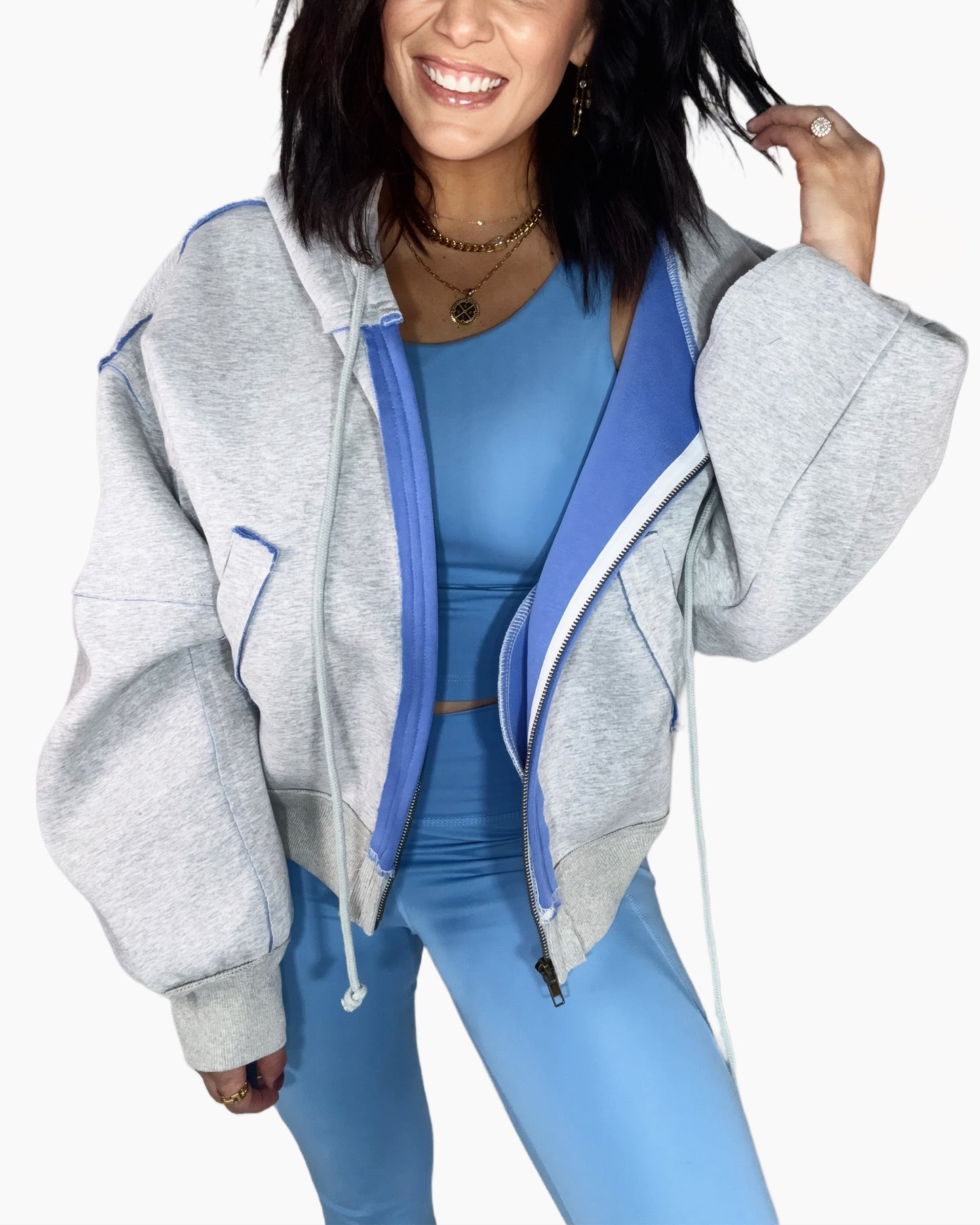 Woman wearing a gray hoodie with blue accents and matching leggings on a white background