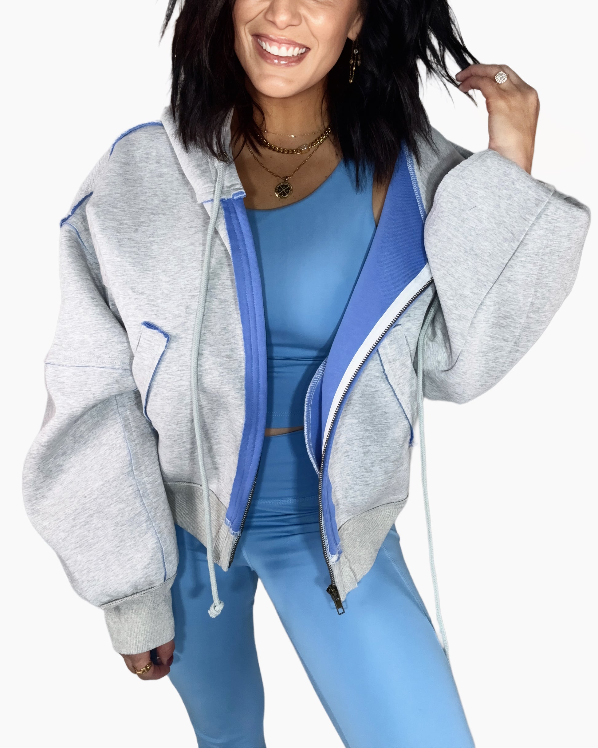 Woman wearing a gray hoodie with blue accents and matching leggings on a white background