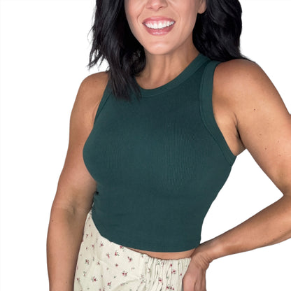 Side profile of a woman wearing a green ribbed tank top, floral shorts, on a white back ground
